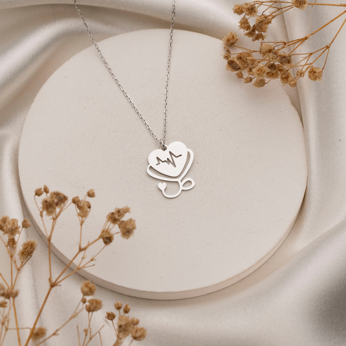 Nurse heartbeat necklace held in hand for scale