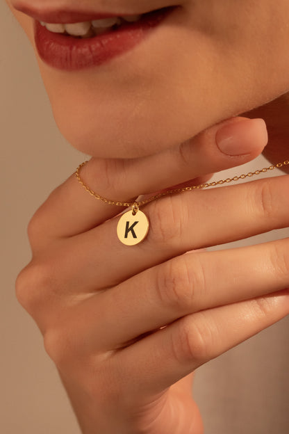 Personalized round initial necklace worn by a woman