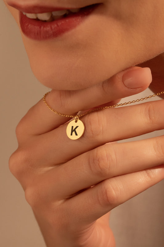 Personalized round initial necklace worn by a woman
