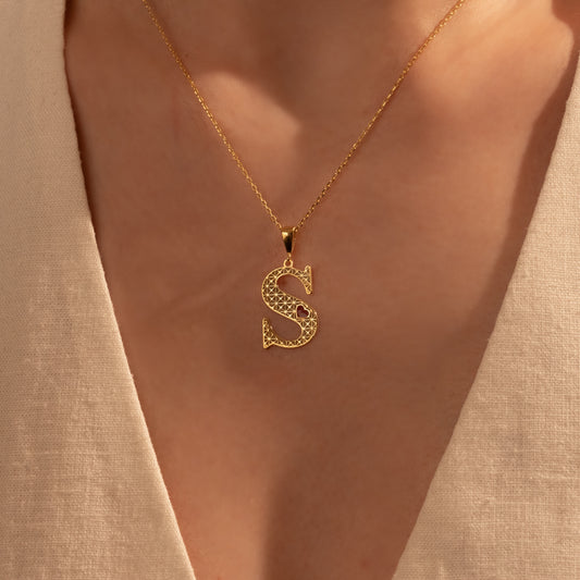 Personalized gold filigree initial necklace worn by a woman