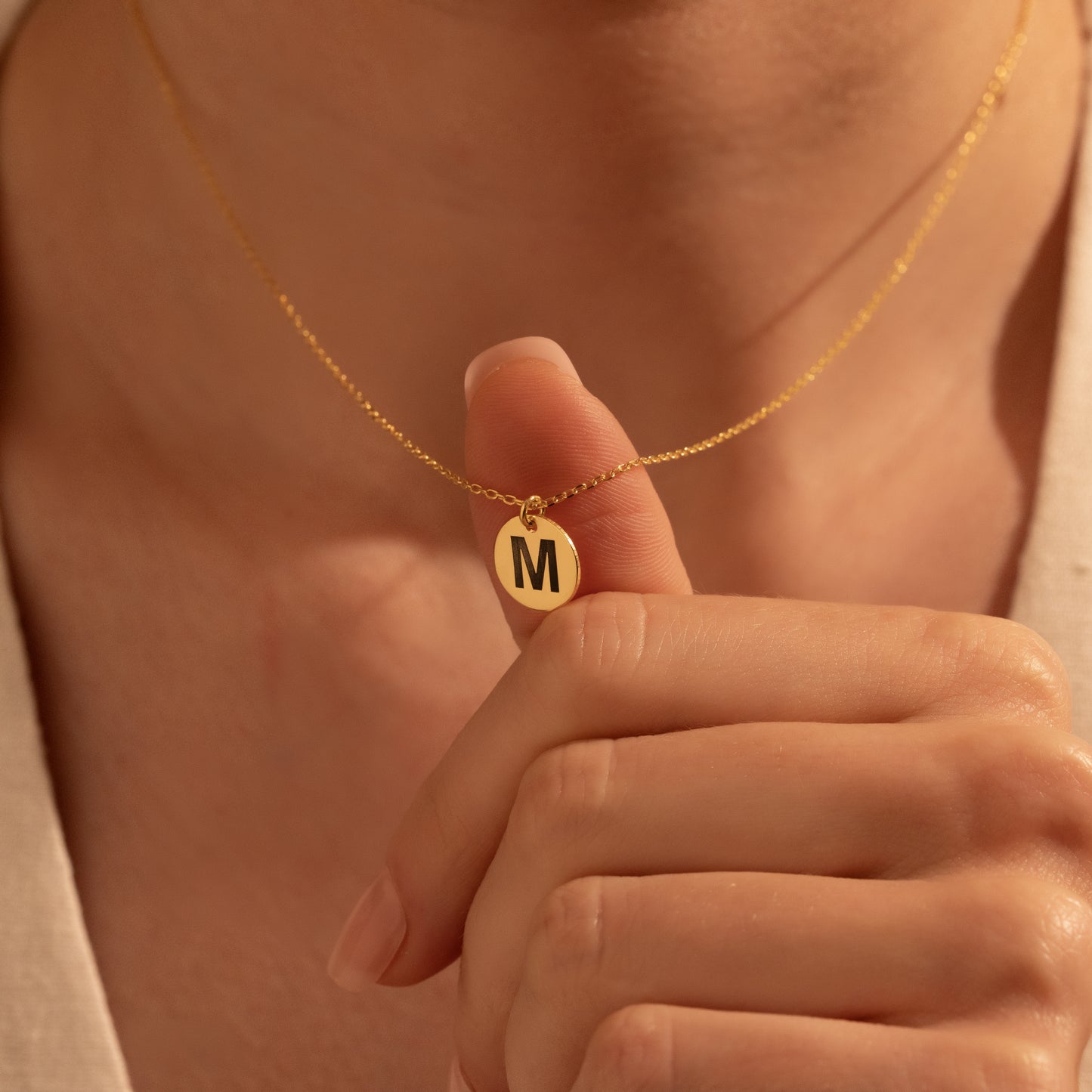 Personalized gold round initial disc necklace worn by a woman