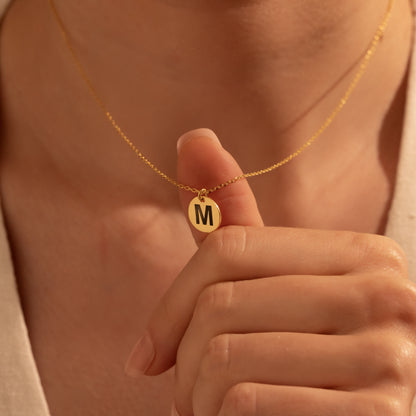 Personalized gold round initial disc necklace worn by a woman