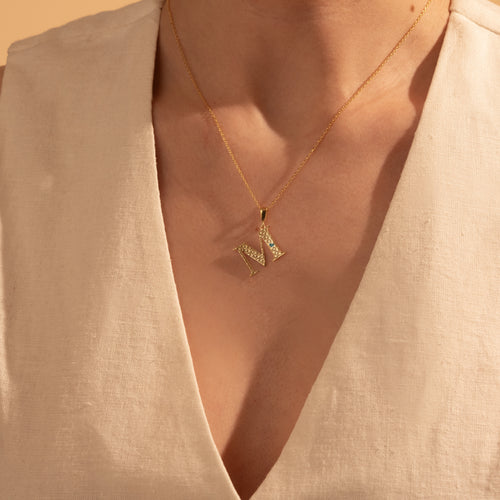 Personalized gold geometric initial necklace worn by a woman
