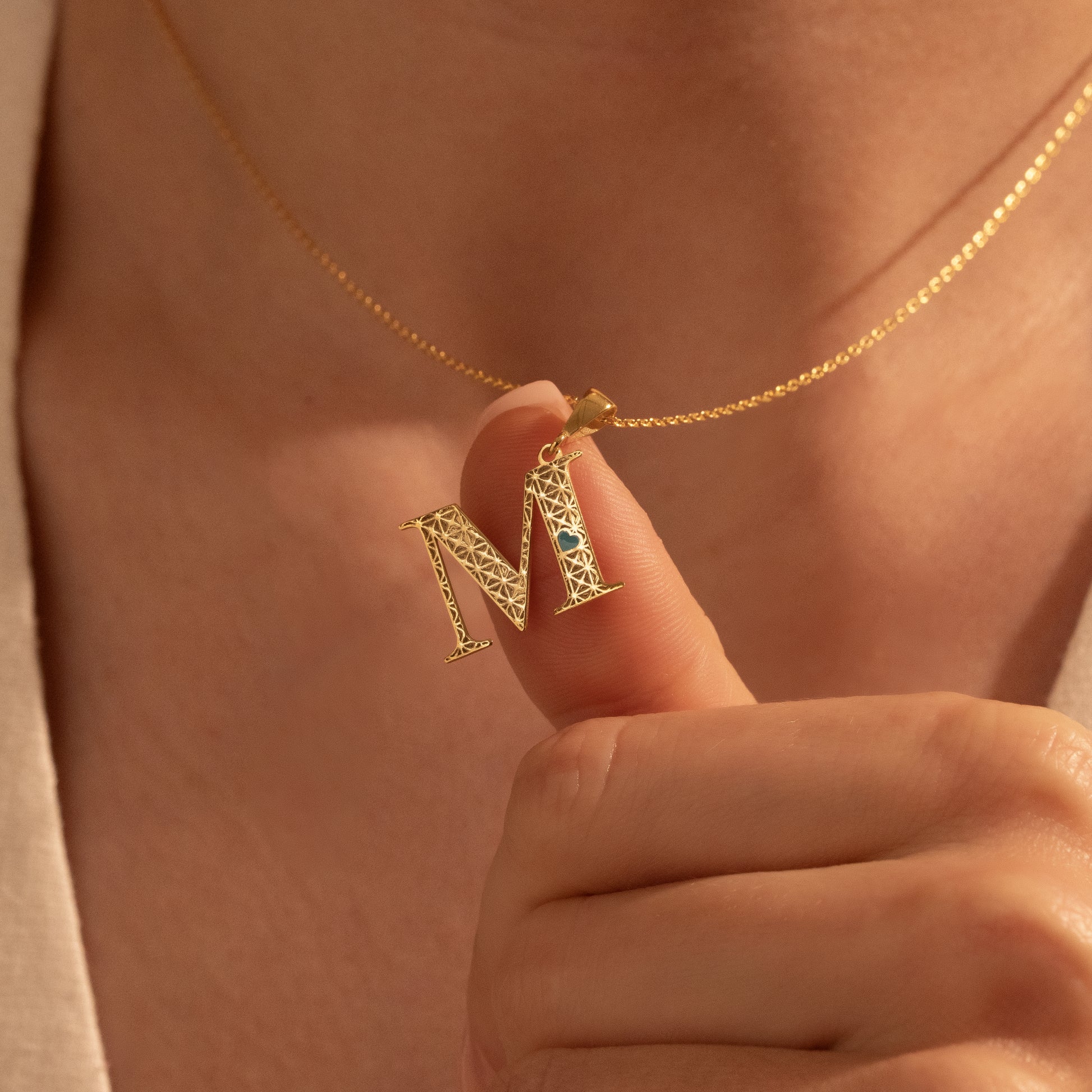 Gold letter M pendant necklace with openwork detailing