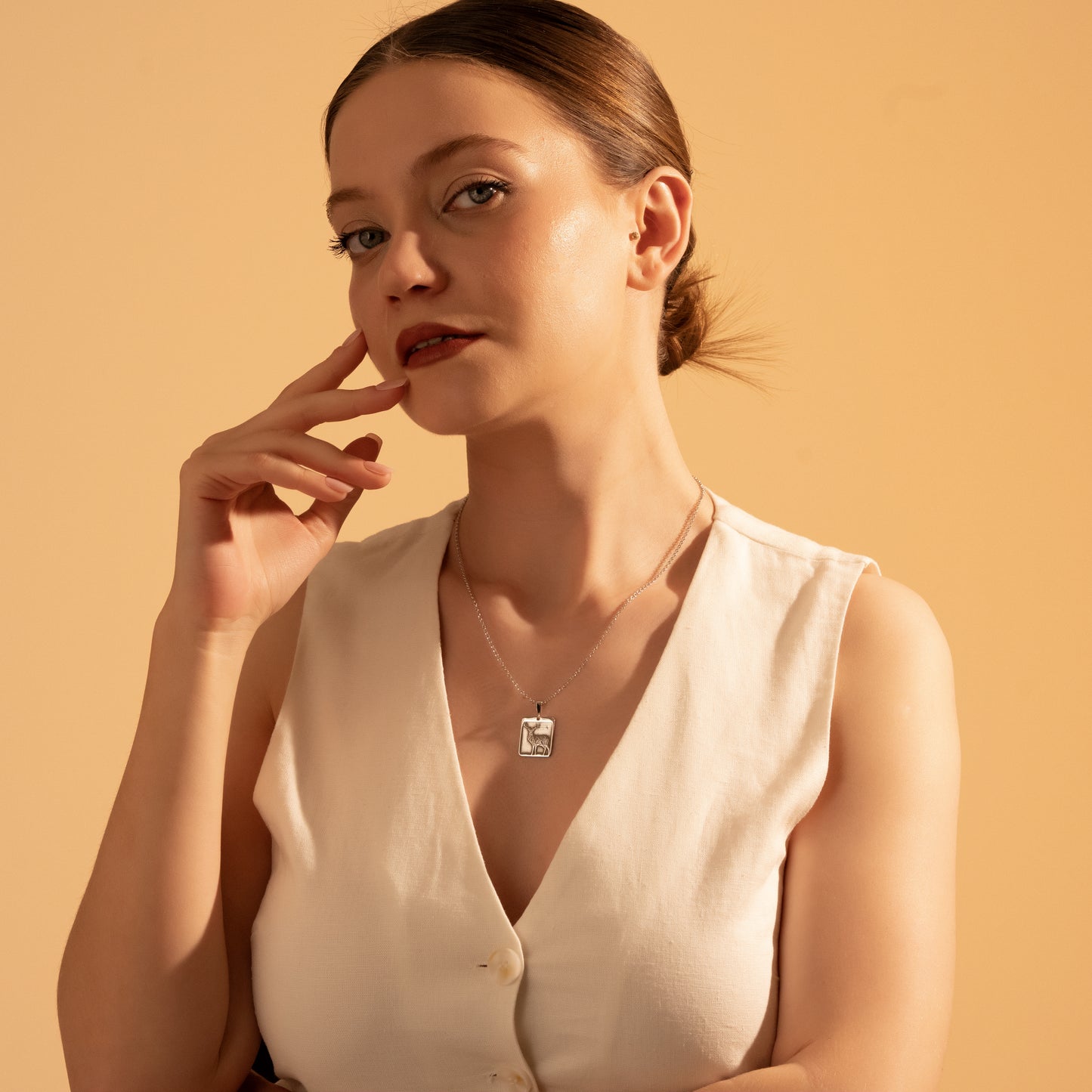 Woodland-inspired framed deer necklace worn by a woman