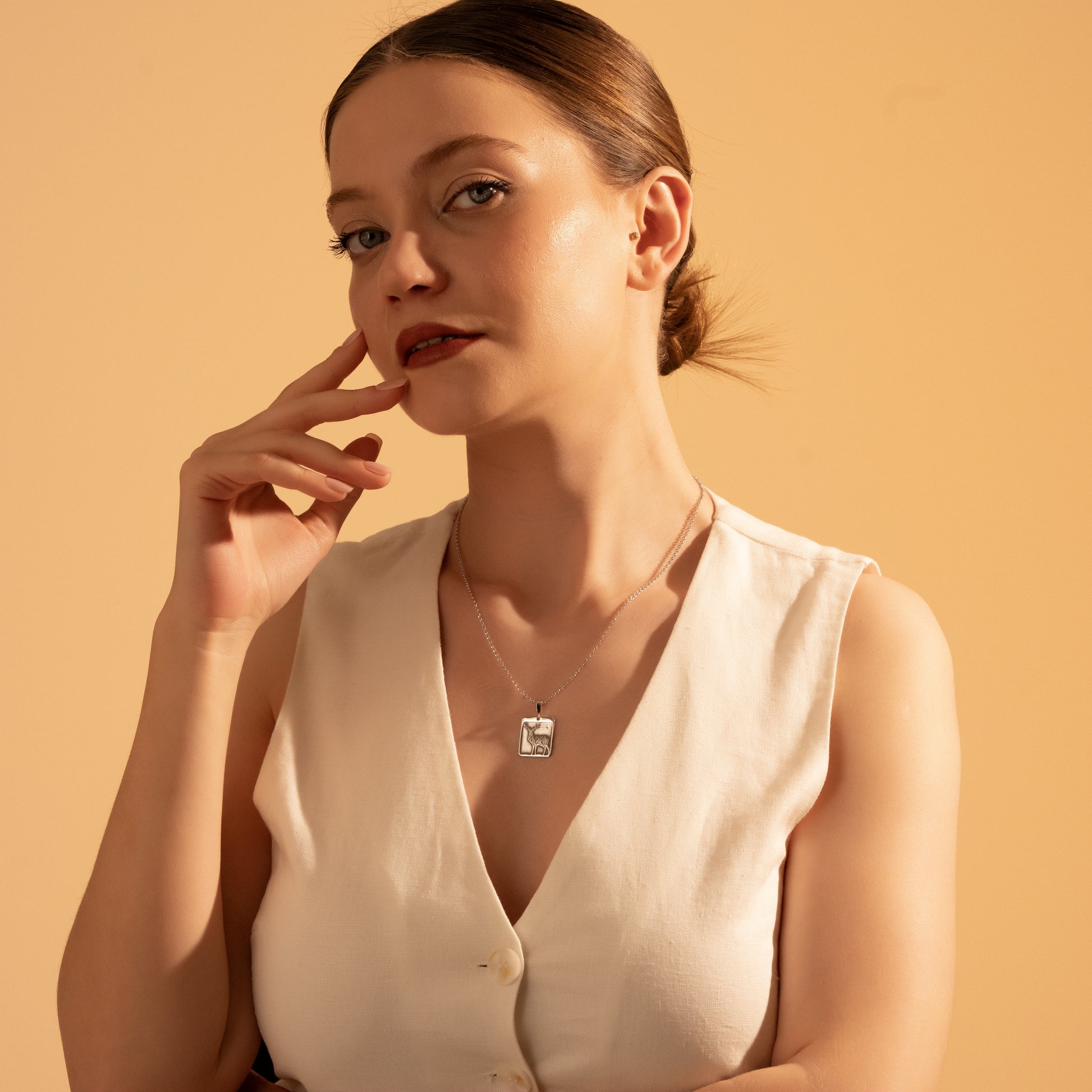 Woodland-inspired framed deer necklace worn by a woman