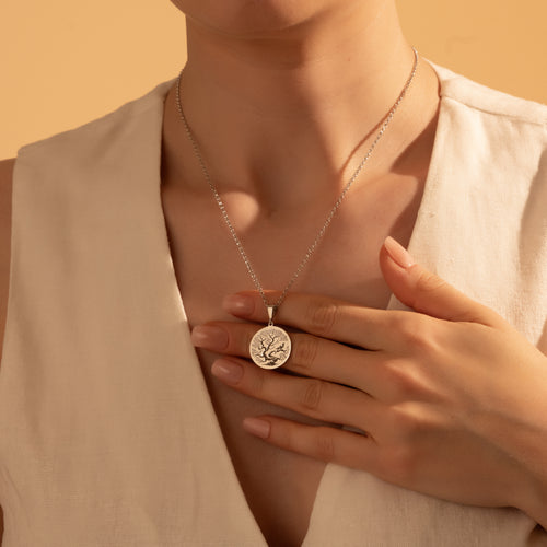 Silver Tree of Life coin necklace worn by a woman