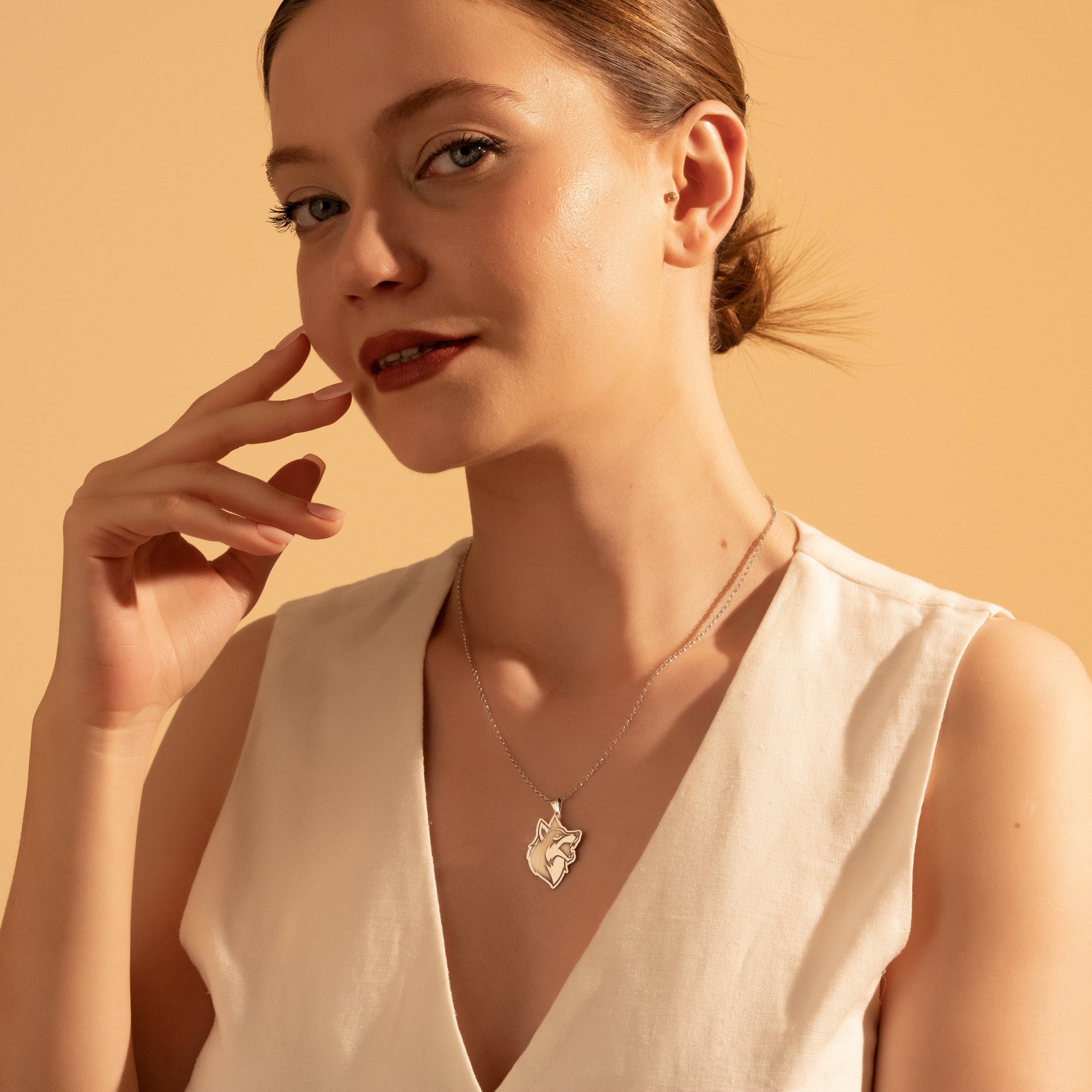 Silver wolf head pendant necklace worn by a woman