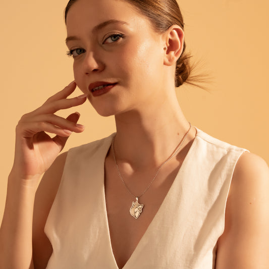 Silver wolf head pendant necklace worn by a woman