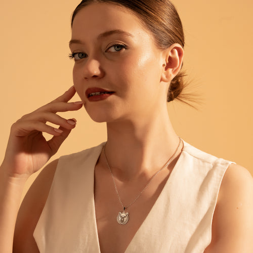 Botanical deer medallion necklace worn by a woman