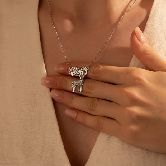 Silver deer pendant necklace worn by a woman