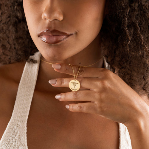 Gold personalized Caduceus name necklace held by model