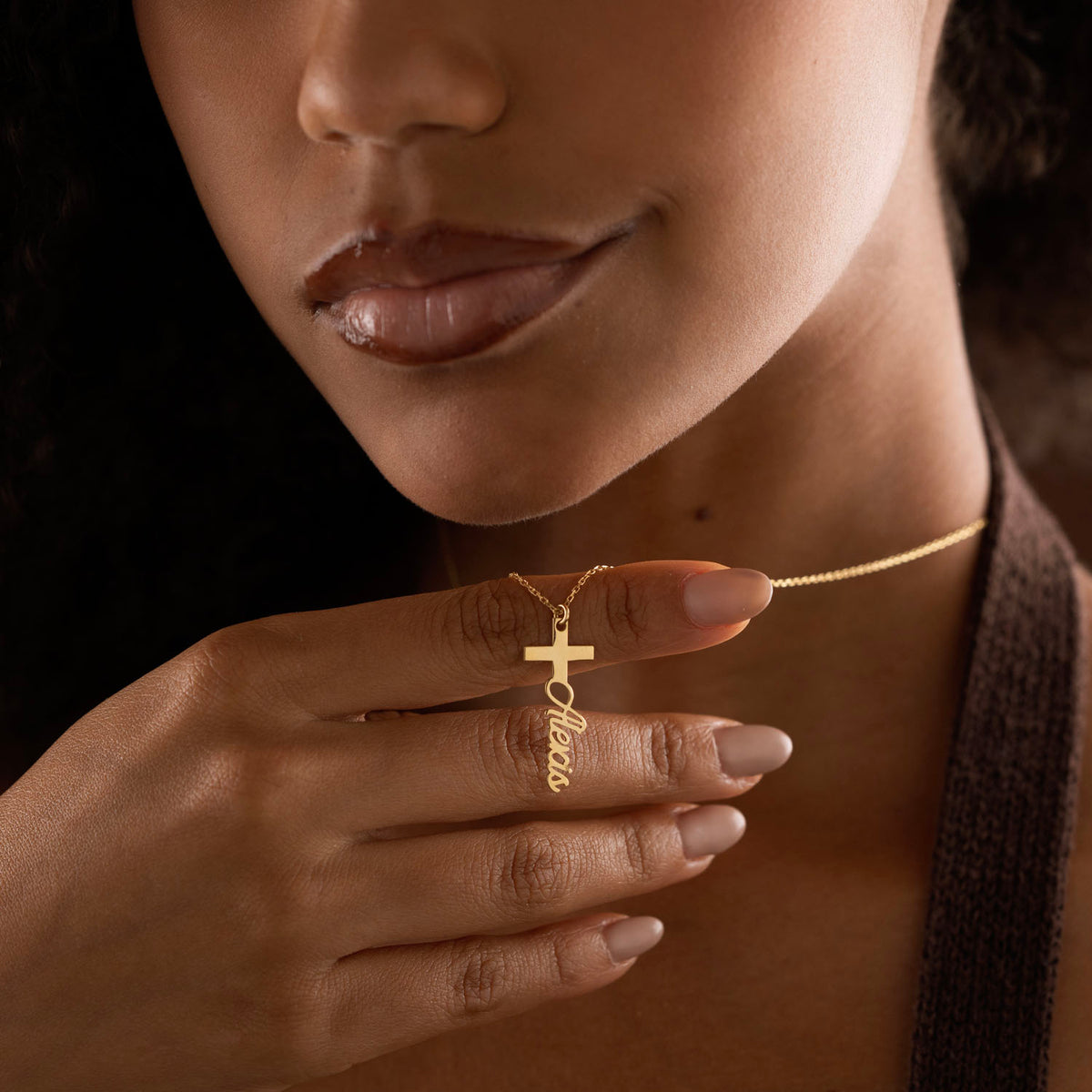 Gold personalized cross name necklace held by model