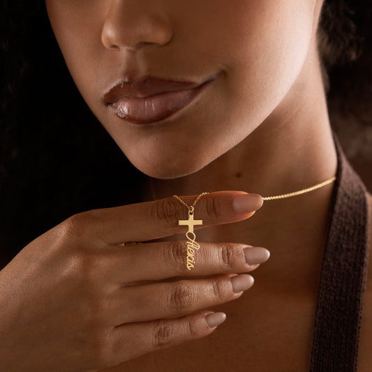 Gold personalized cross name necklace held by model