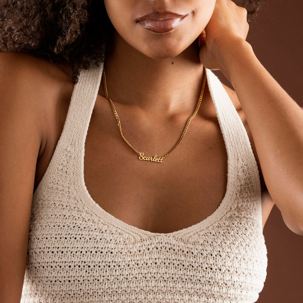Curb chain name necklace worn by woman