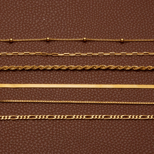 18K gold plated chain necklace styles laid flat on brown leather