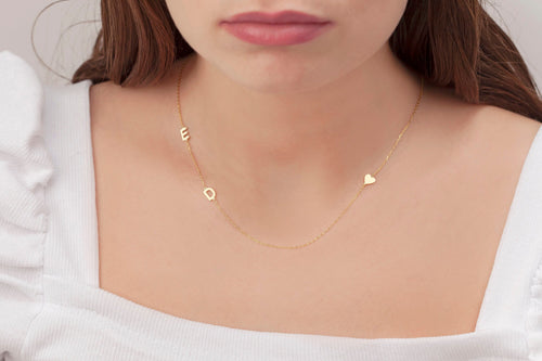 Sideways initial necklace in gold worn on the collarbone