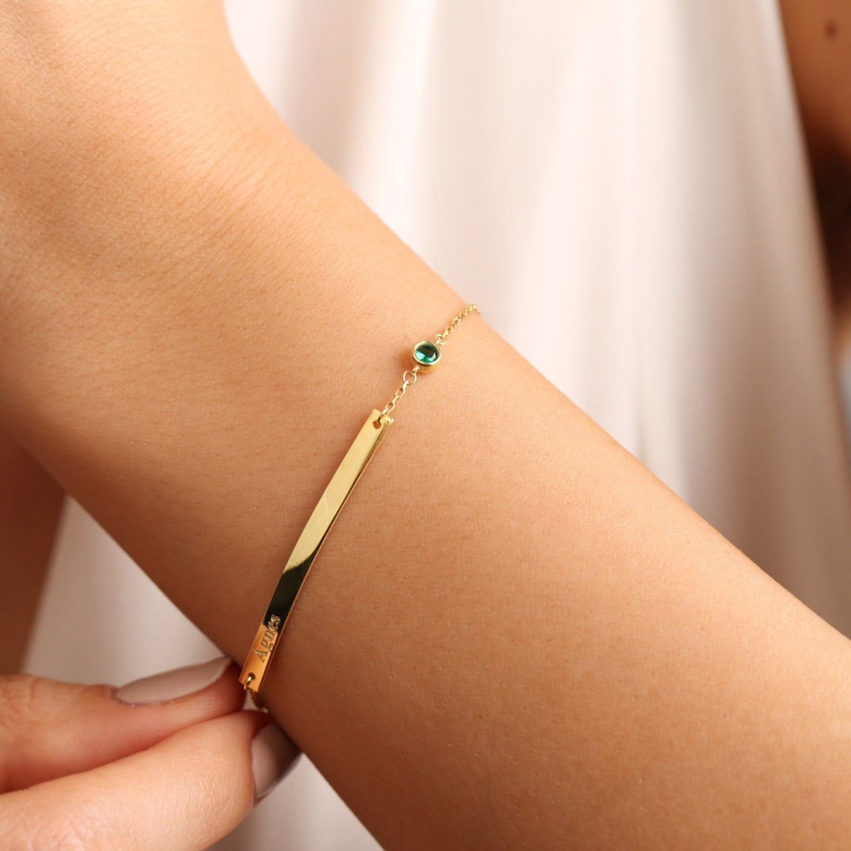 Engraved bar bracelet in gold with a birthstone on the wrist