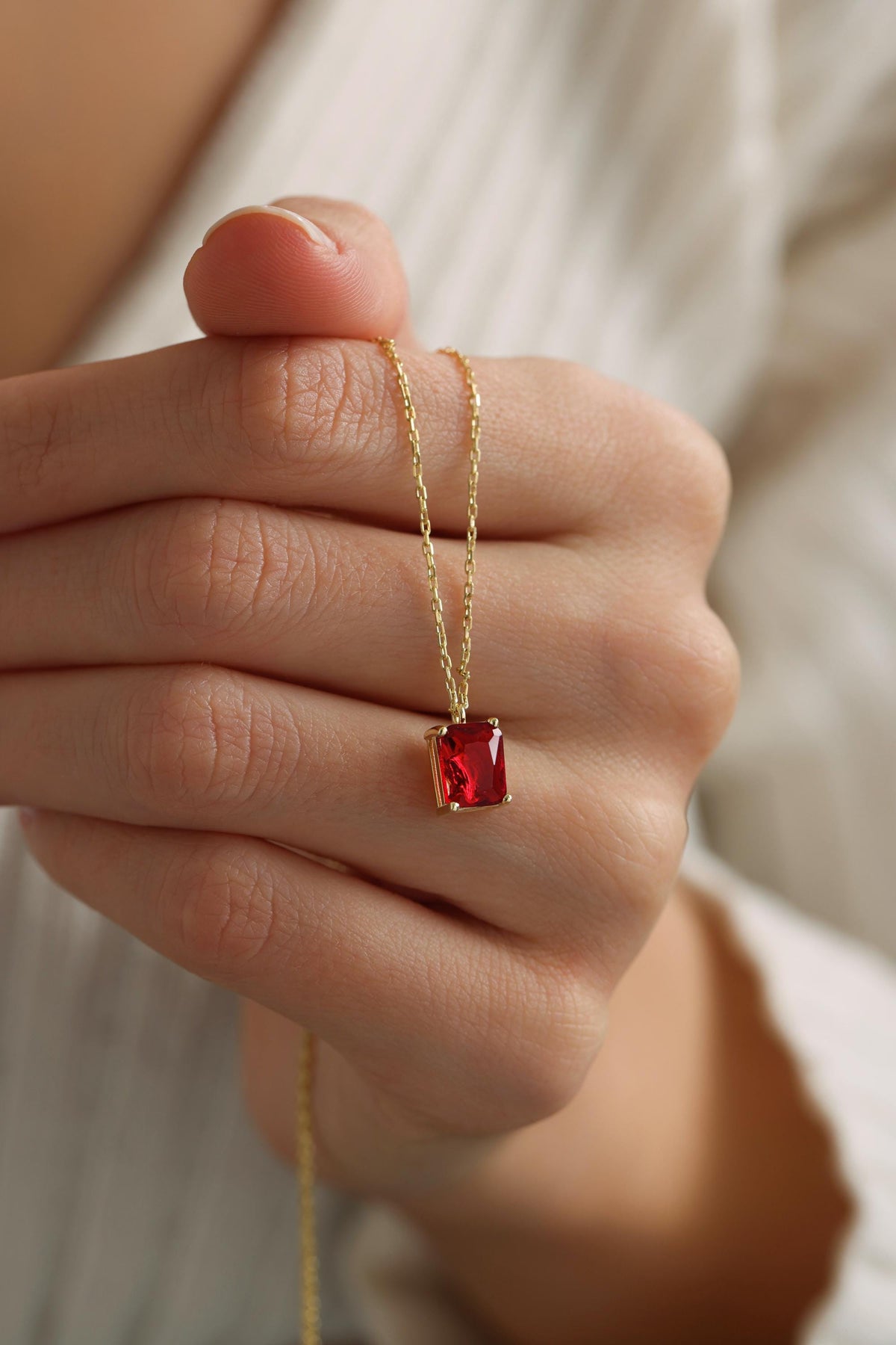 Emerald cut stone necklace held in hand