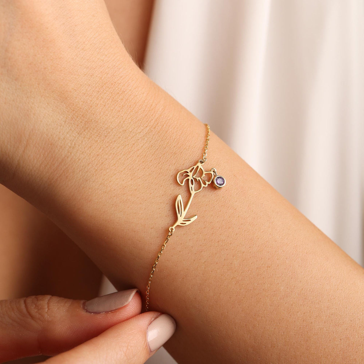 Birth flower bracelet in gold with a birthstone worn on the wrist