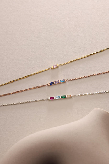 Baguette birthstone bracelets laid flat in three finishes
