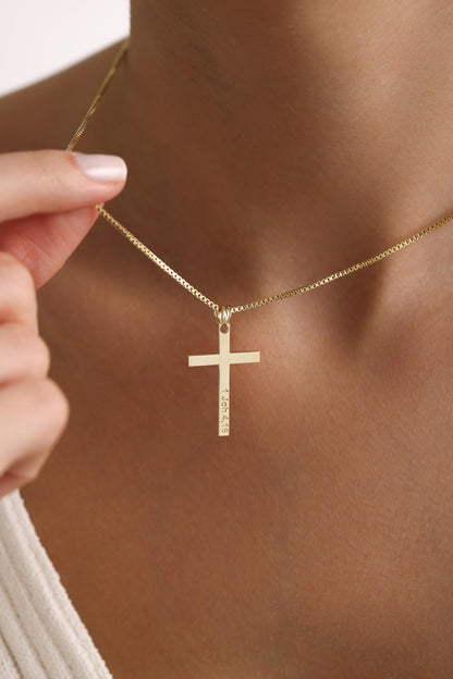 Pave cross necklace in gold held against the neck