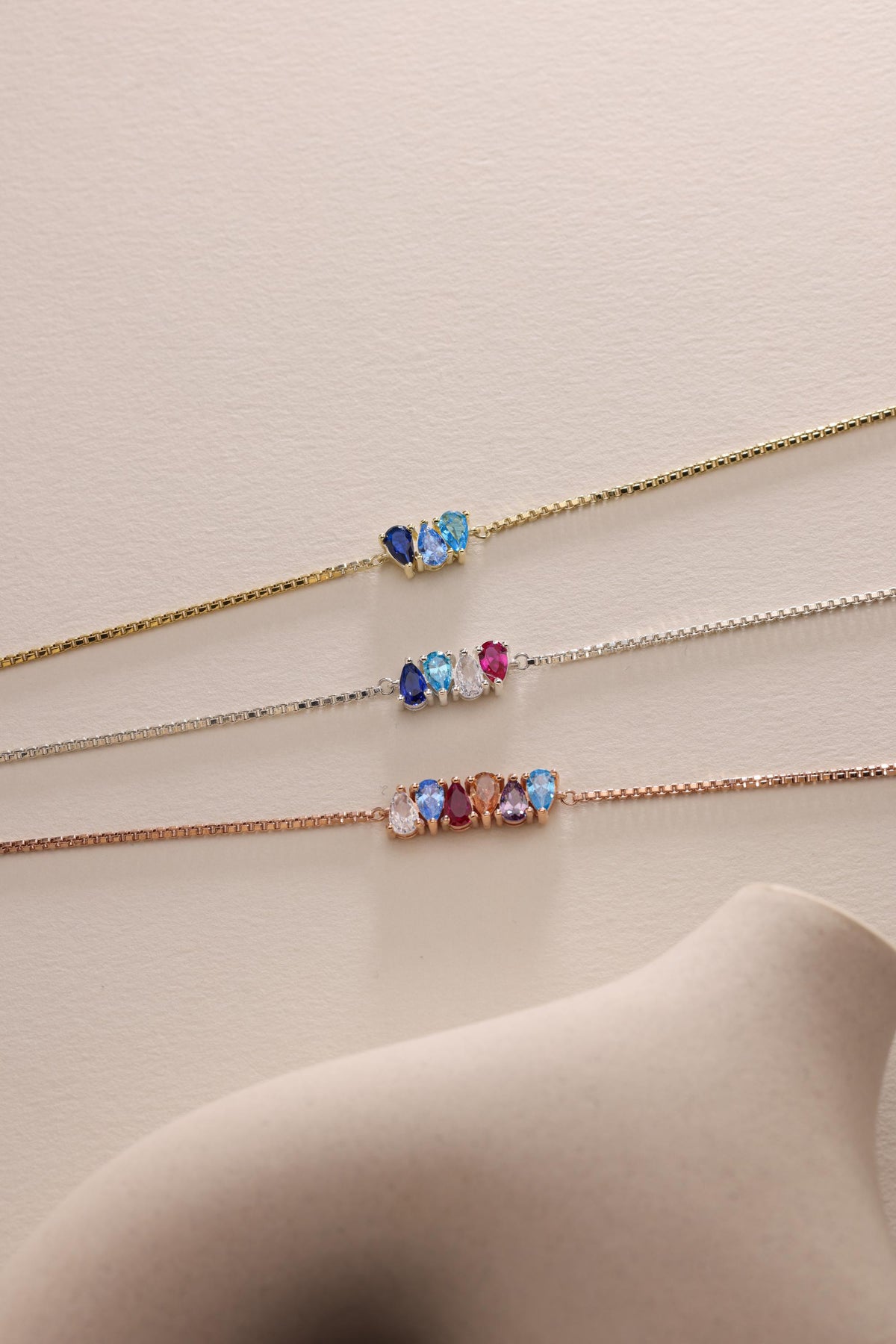 Teardrop birthstone bracelets in several colours laid flat