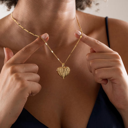 Textured heart pendant necklace held up by a woman