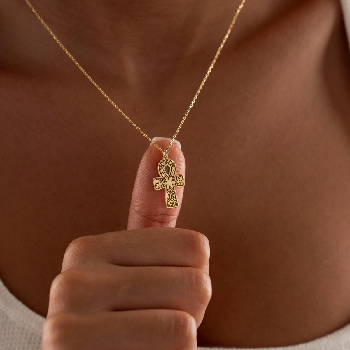 Egyptian ankh necklace held up by a woman
