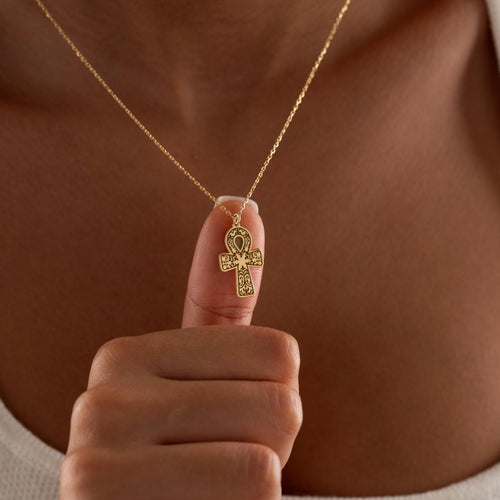 Egyptian ankh necklace held up by a woman