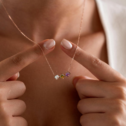 Birthstone cluster necklace held up by a woman