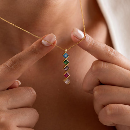 Square multi birthstone necklace held up by a woman