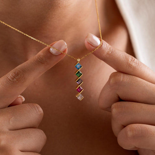 Square multi birthstone necklace held up by a woman