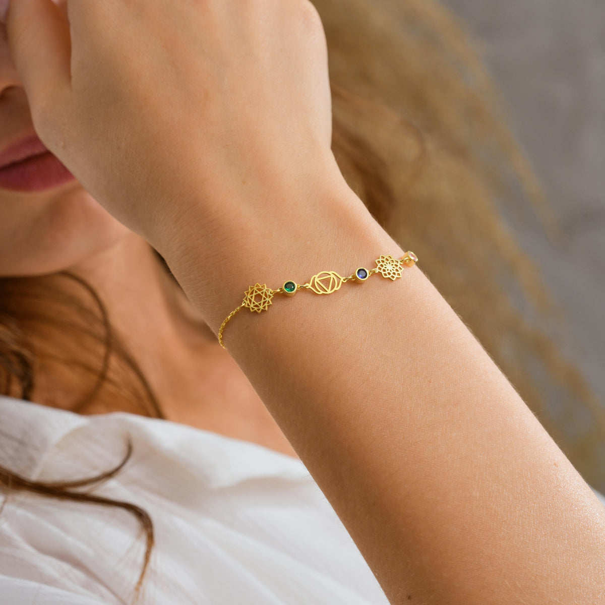 Chakra bracelet in gold with seven coloured stones on the wrist