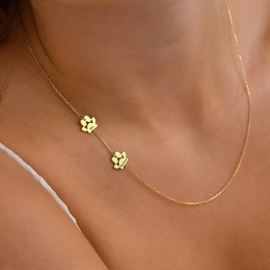 Sideways paw print necklace in gold worn on the collarbone