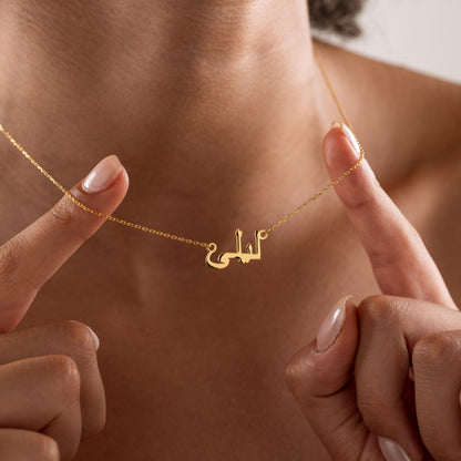 Arabic calligraphy name necklace held up by a woman