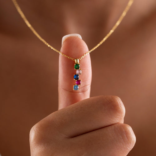 Vertical family birthstone necklace held up by a woman