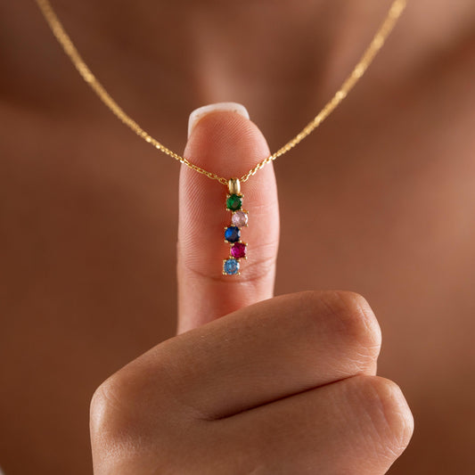 Vertical family birthstone necklace held up by a woman