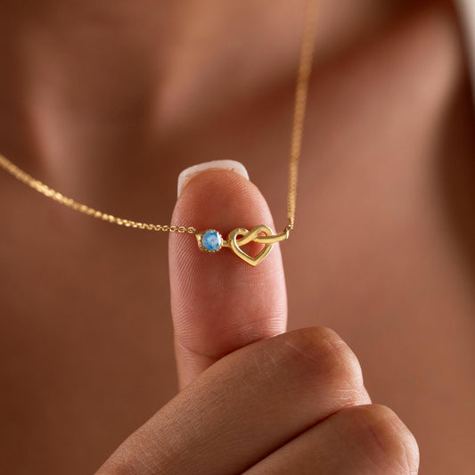 Heart birthstone necklace held up by a woman