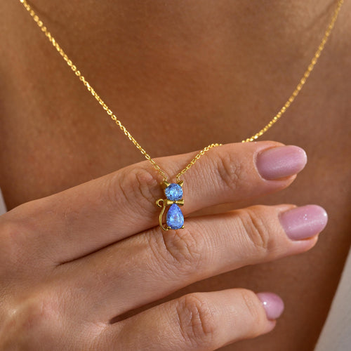 Cat birthstone necklace held up by a woman