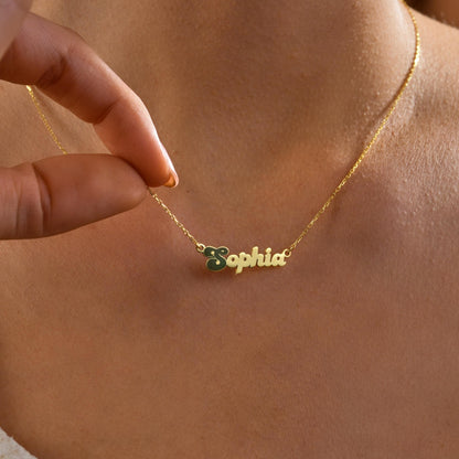Name necklace with an enamel initial charm worn on the neck