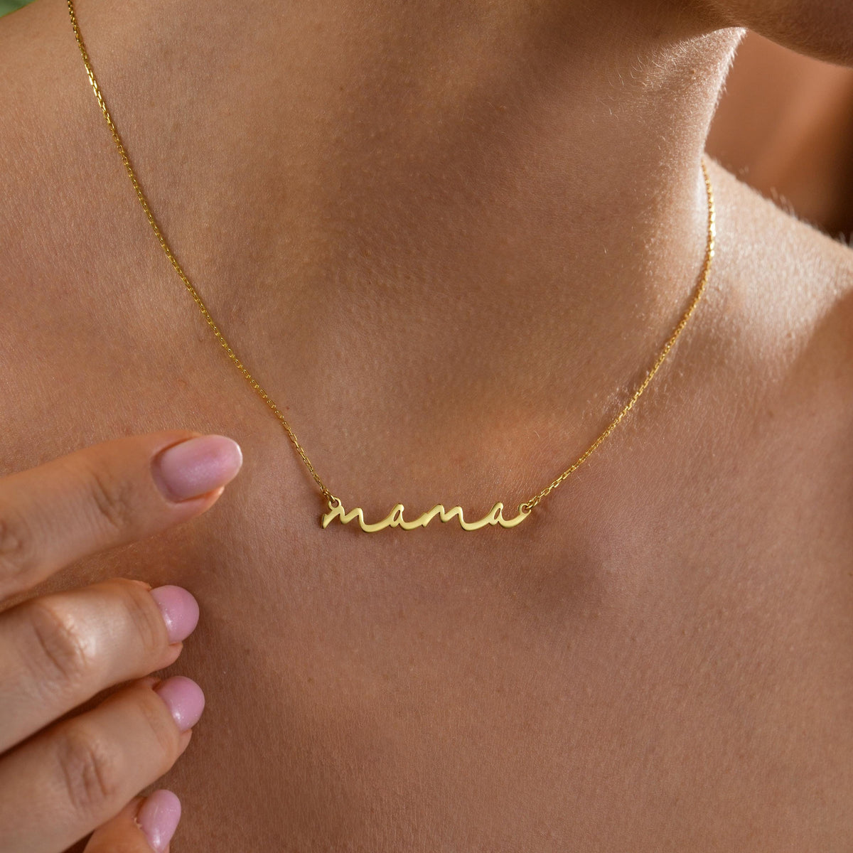 Script nana necklace held up by a woman