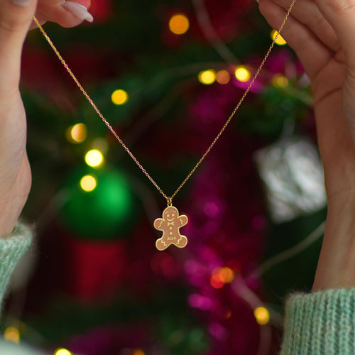 Personalized gingerbread man necklace held up by a woman
