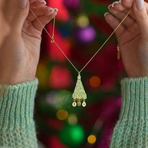 Christmas tree necklace with dangling charms held up by a woman