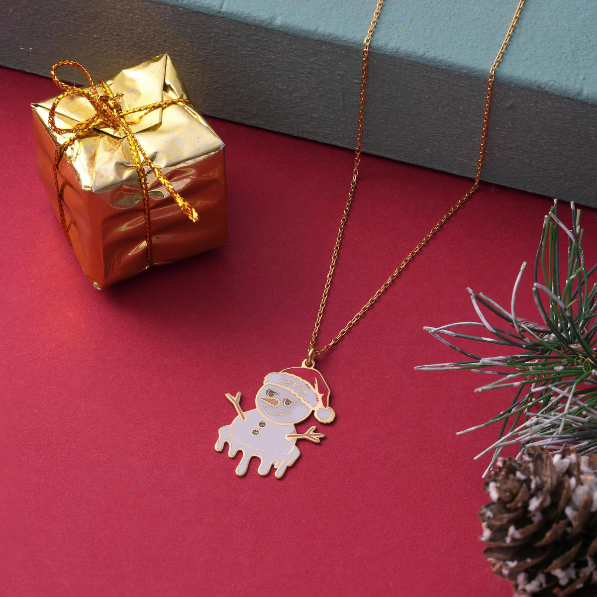 Melting snowman name necklace shown against a holiday background