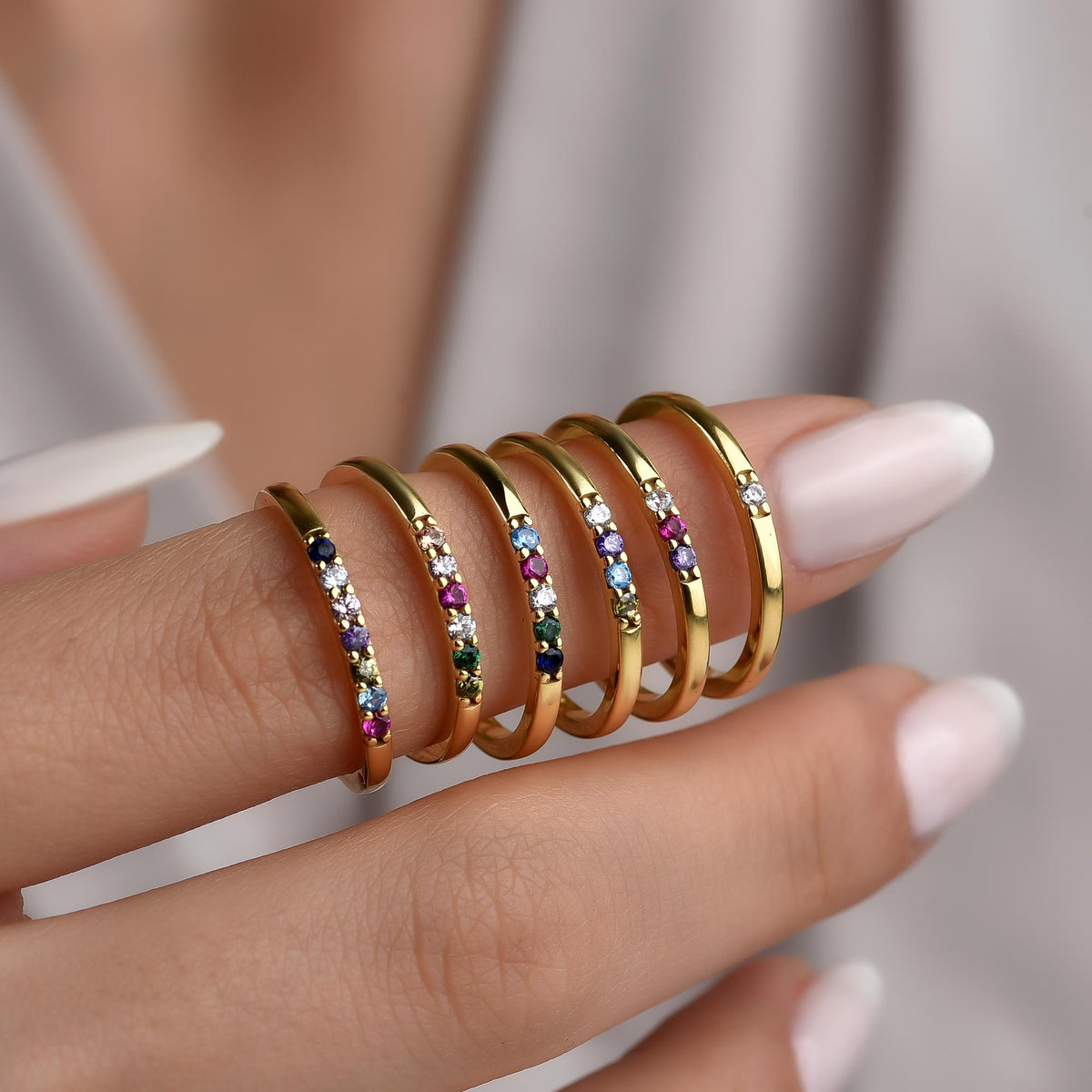 Dainty birthstone rings stacked across several months