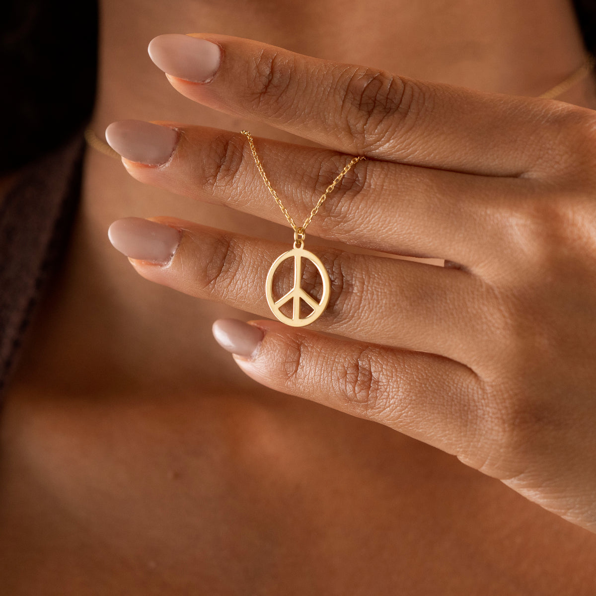 Gold-tone peace necklace worn as everyday jewelry