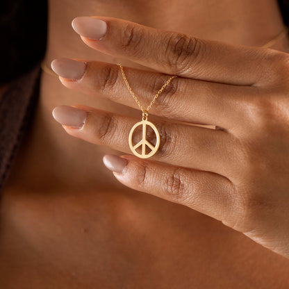 Gold-tone peace necklace worn as everyday jewelry
