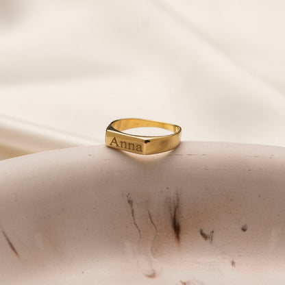Engraved 18K gold plated name ring on a stone display