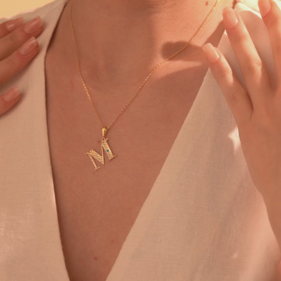 Gold letter M pendant necklace with openwork detailing
